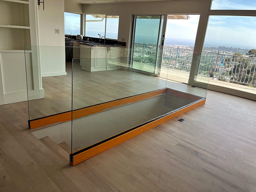 An oversized glass panel resting on blocks before installation, harbour view beyond